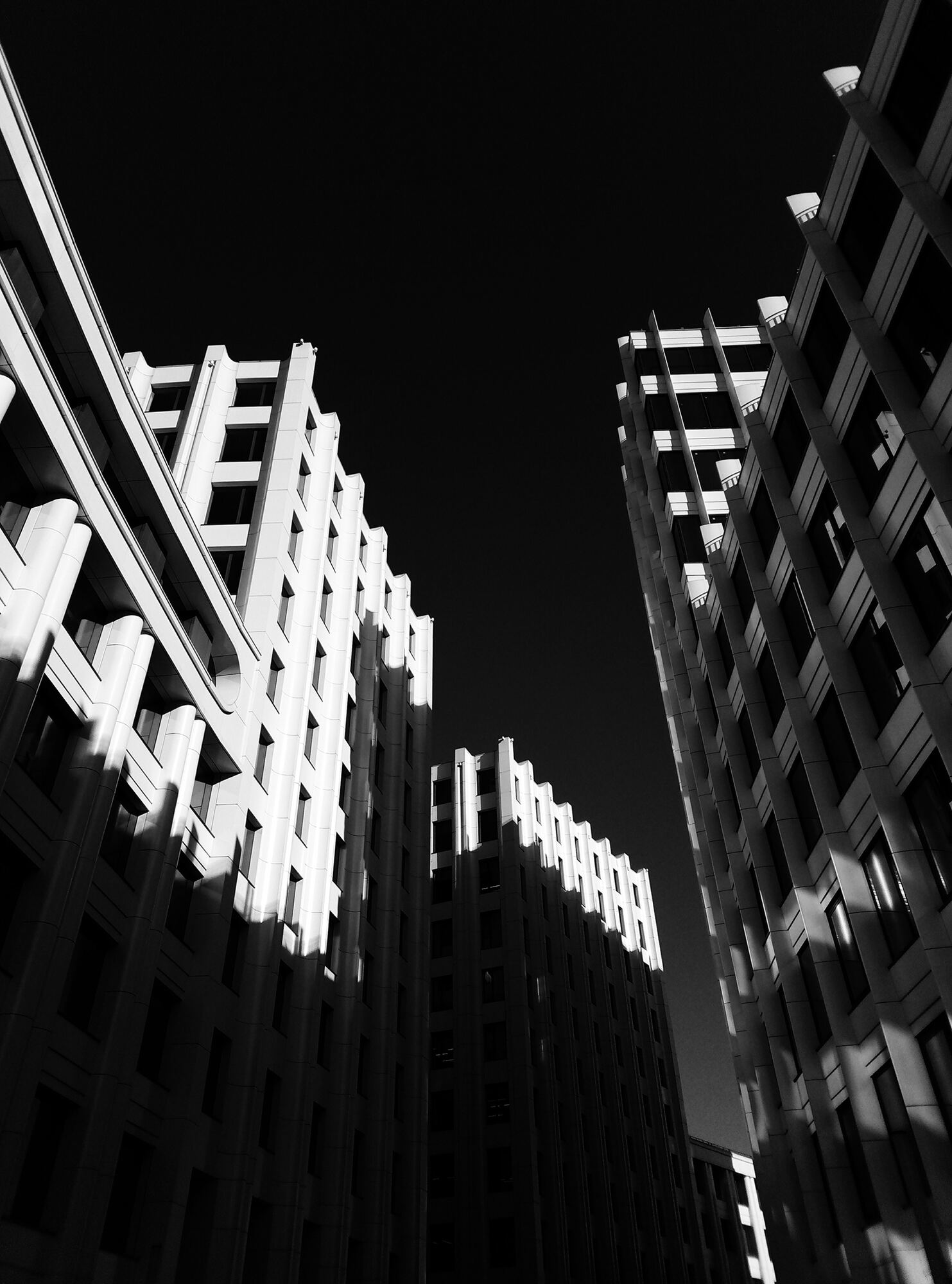 Low-angle black and white view of stone office towers against a dark sky